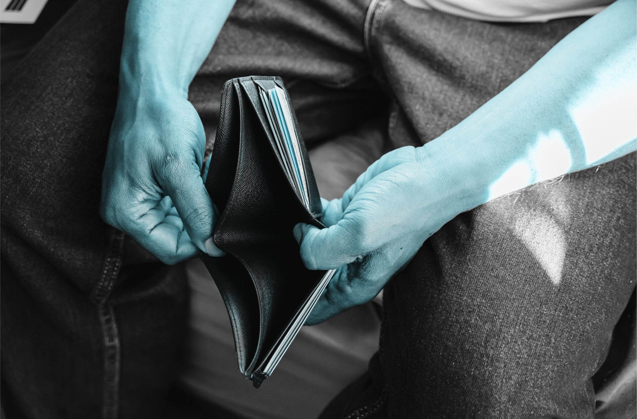 man opening wallet with nothing in it, but the man's skin color is blue to show he's sad about spending money